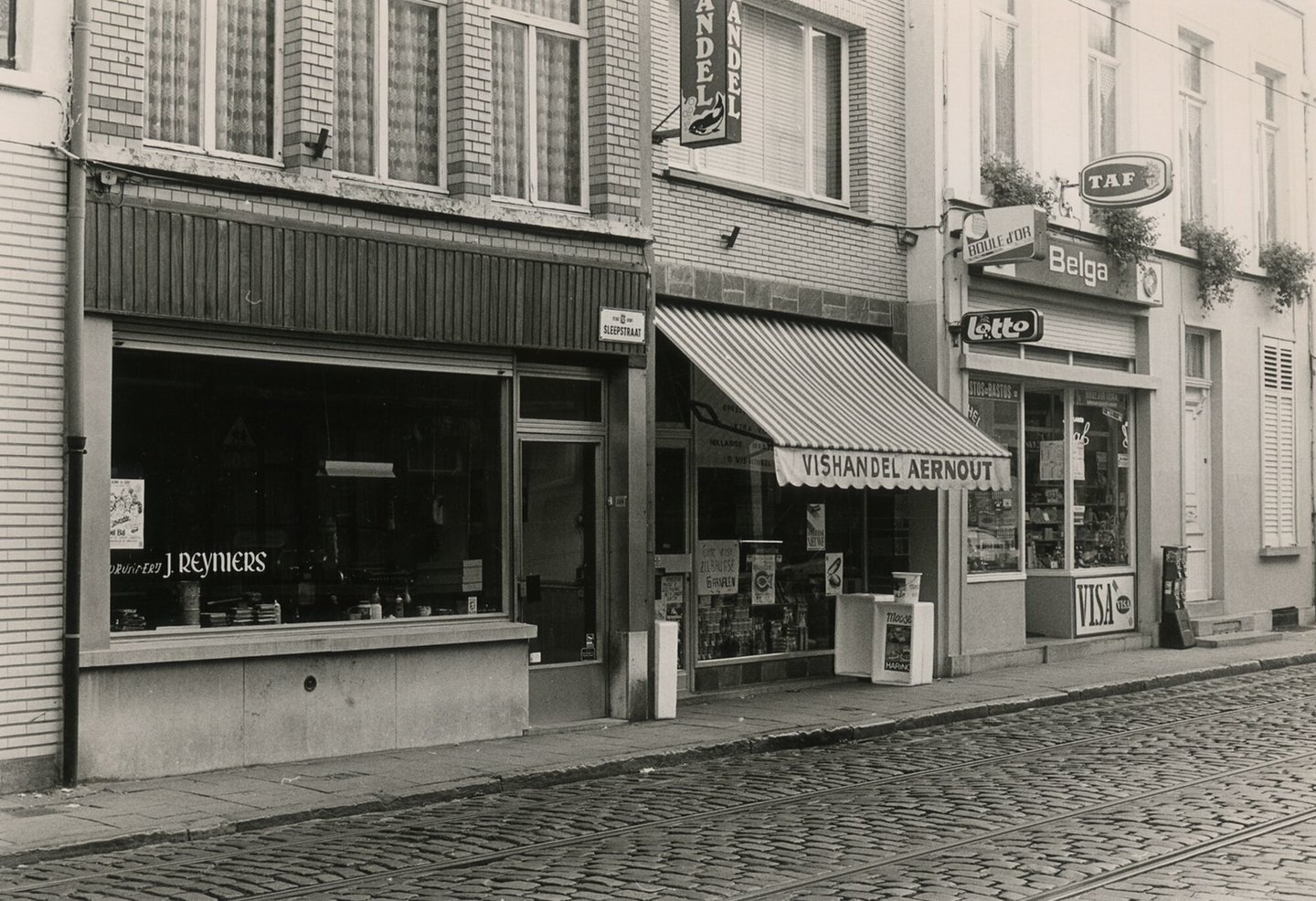 Straatbeeld met etalage van drukkerij Reyniers, vishandel Aernout, en een rookwarenwinkel in Gent