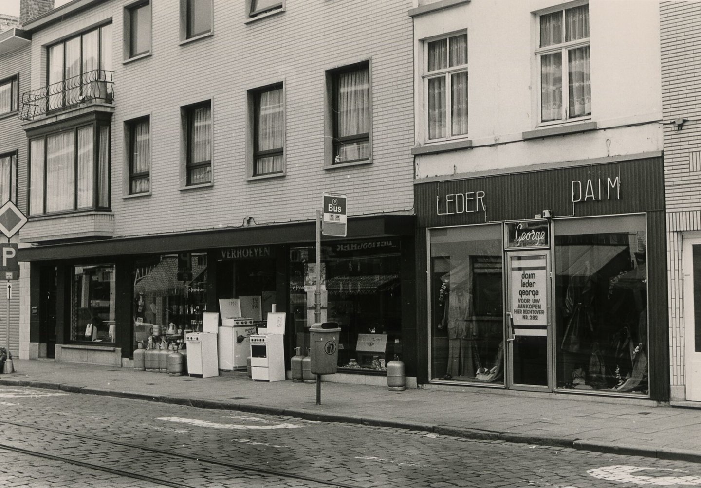 Straatbeeld met etalage van huishoudwinkel Verhoeyen en kledingwinkel - lederwaren George in Gent