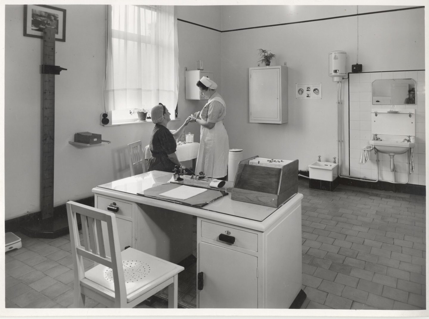 Bedrijfsverpleegster verzorgt een textielarbeidster in de infirmerie van een UCO-vestiging