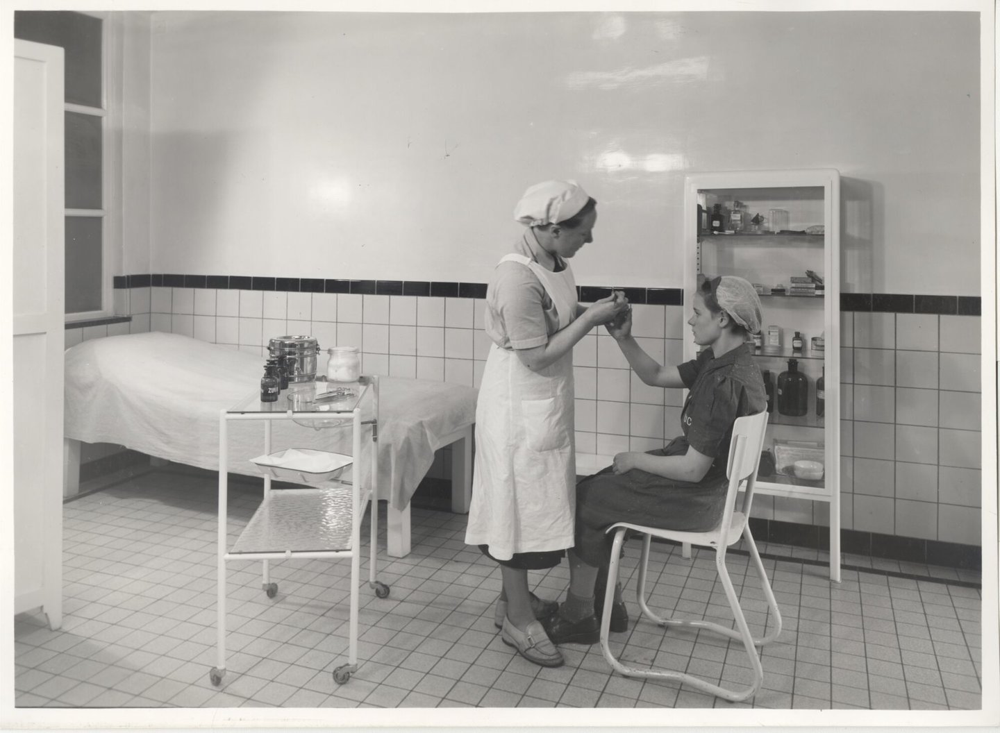 Bedrijfsverpleegster verzorgt een textielarbeidster in de infirmerie van een UCO-vestiging