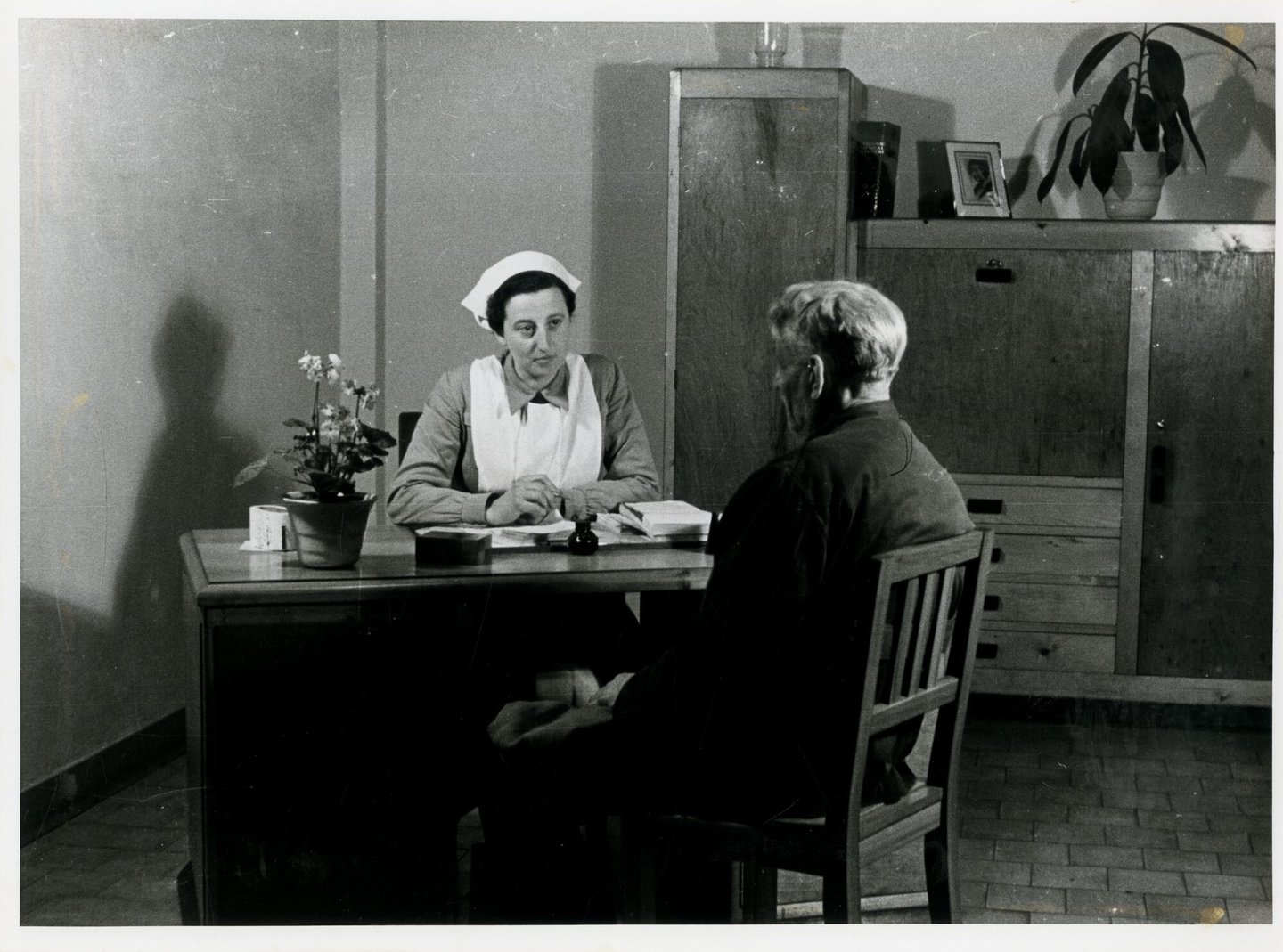 Bedrijfsverpleegster in gesprek met een textielarbeider bij textielfabriek de Hemptinne in Gent