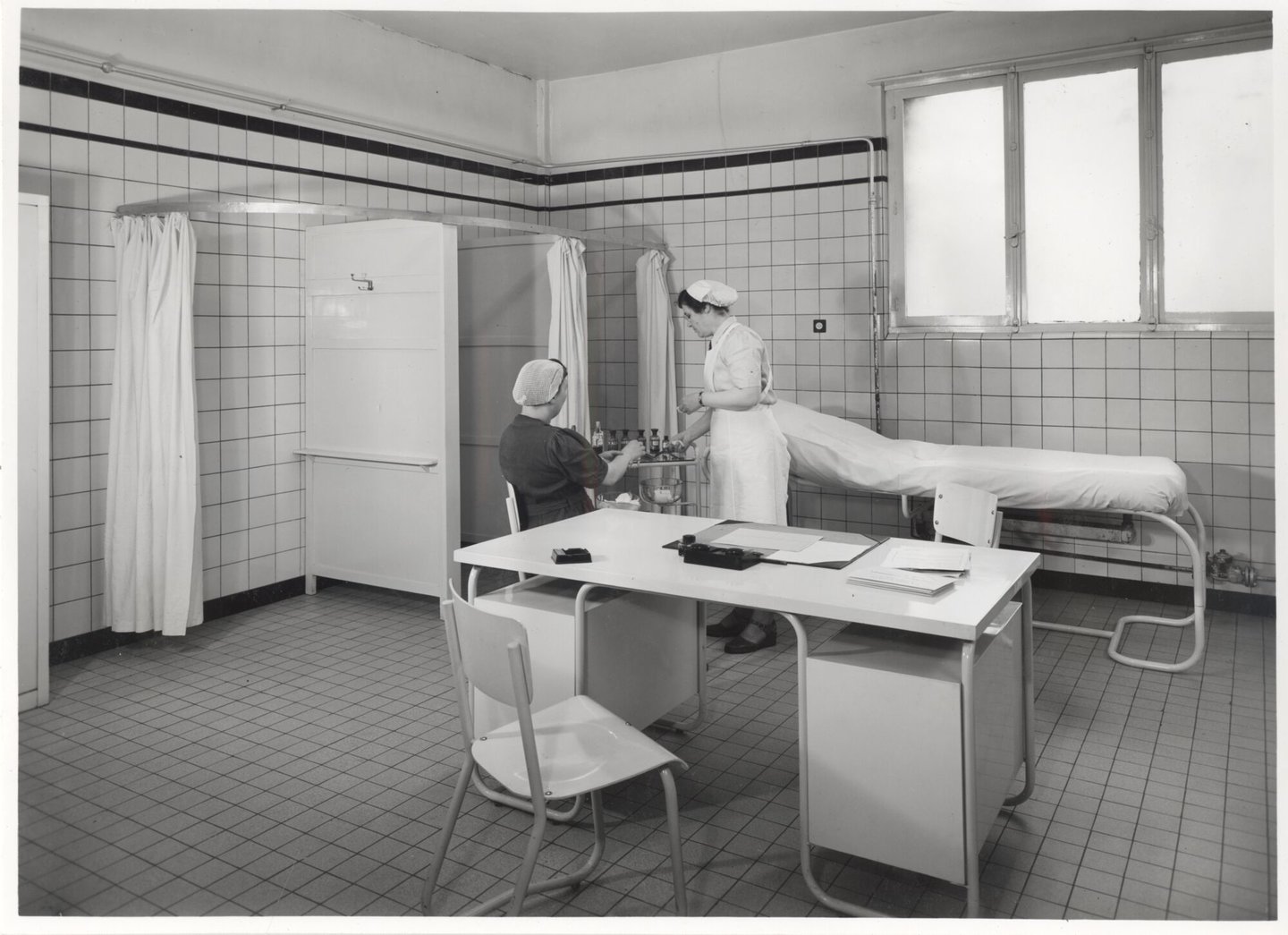 Bedrijfsverpleegster verzorgt een textielarbeidster in de infirmerie van een UCO-vestiging