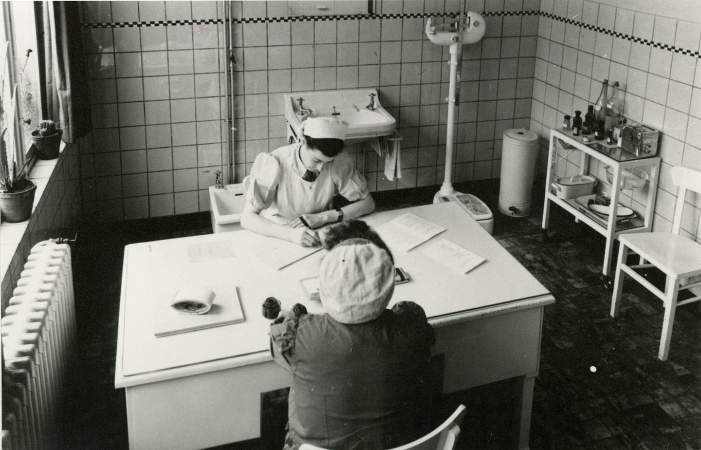 Bedrijfsverpleegster in gesprek met textielarbeidster in de infirmerie van UCO Desmet-Guequier in Gent