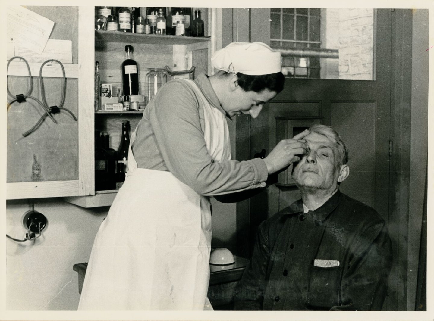 Bedrijfsverpleegster verzorgt een textielarbeider in de infirmerie van 
textielfabriek de Hemptinne in Gent