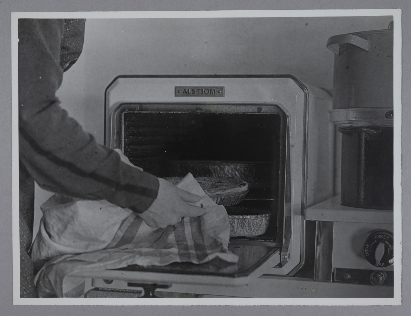 Vrouw haalt een taart uit een elektrische oven van het merk Alsthom