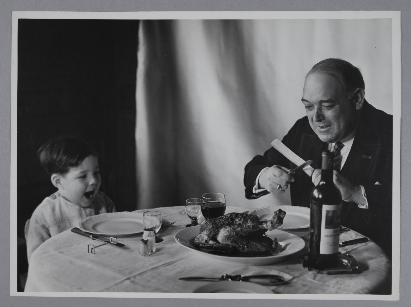 Vader slijpt mes om een gebraden kip aan te snijden