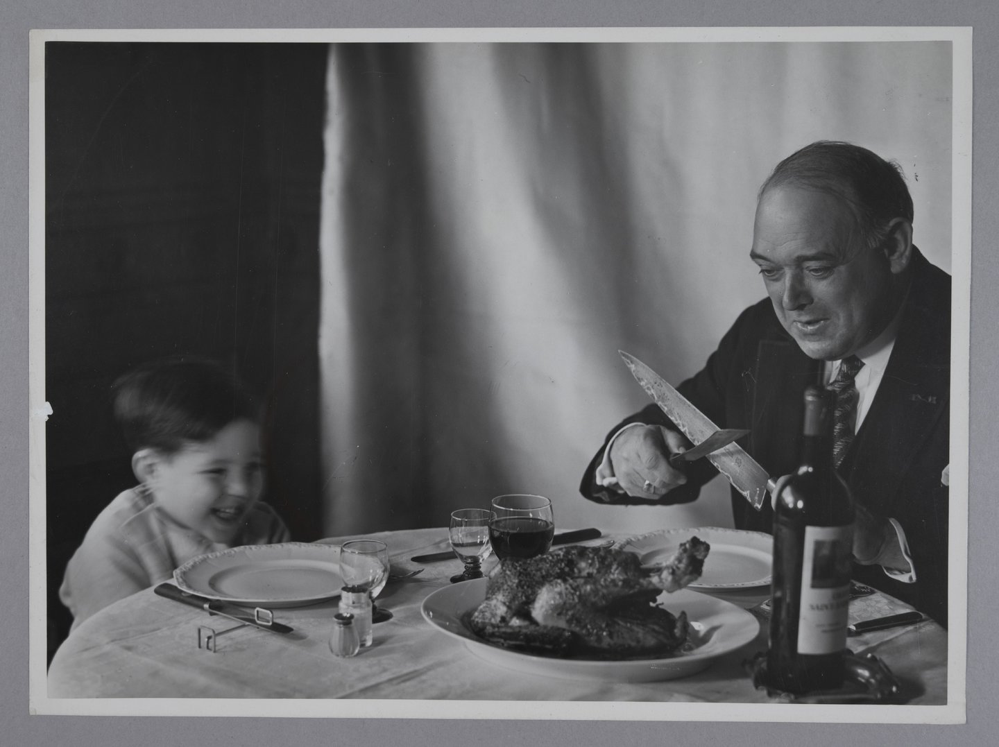 Vader slijpt mes om een gebraden kip aan te snijden