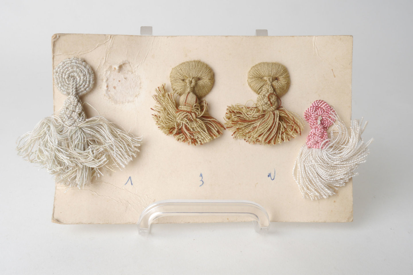 Staalkaart met macarons of rozetten met kwast als onderdeel voor het vervaardigen van passement