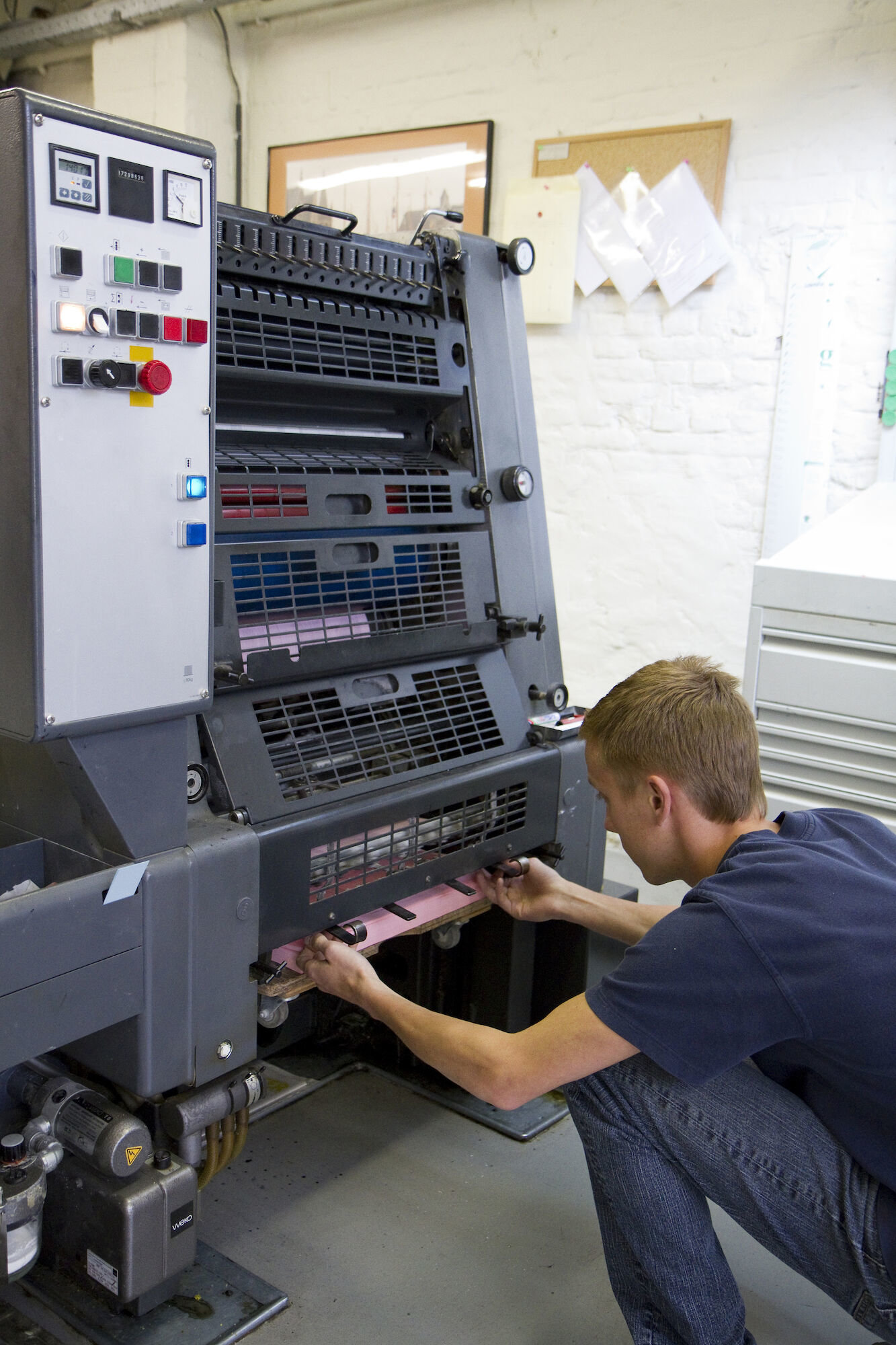 Een leerling-drukker aan een offsetpers in drukkerij Geltmeyer te Gent