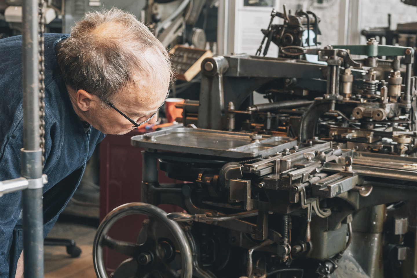 Een drukkerijvrijwilliger bestudeert de Monotype-machine in de drukkerijafdeling van het Industriemuseum