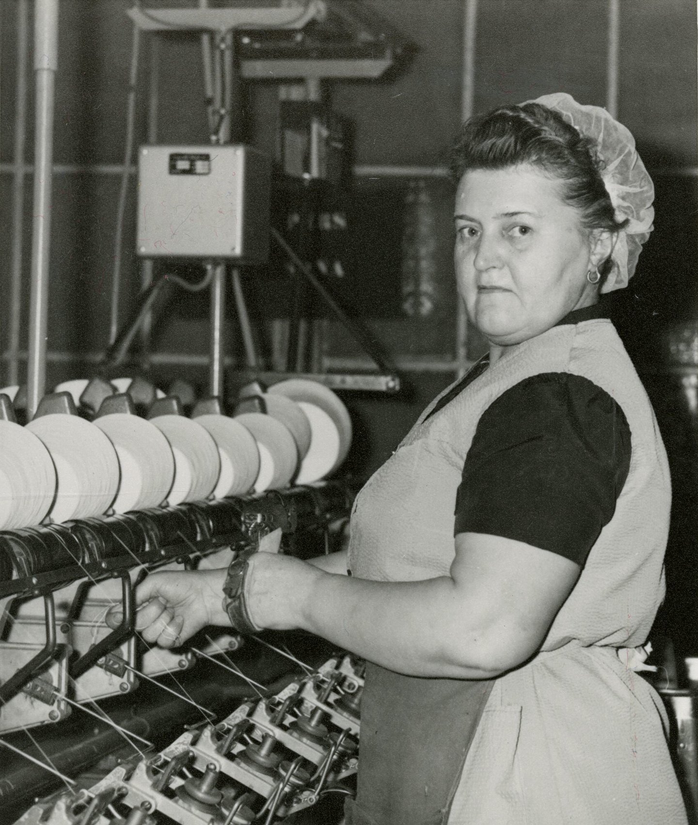 Arbeidster aan een bobijnmachine in UCO Desmet-Guequier